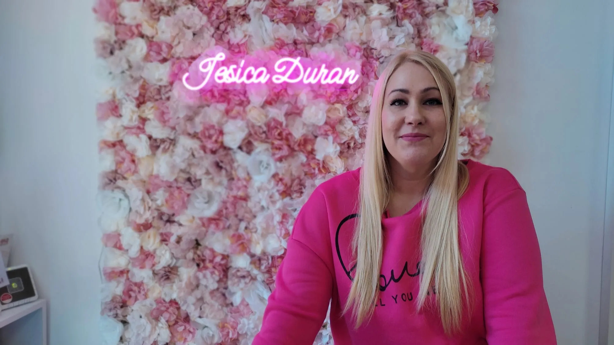 Jesica Durán frente al mural floral de su salón
